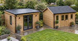 Two single-storey timber garden buildings in a UK garden, one with a dark membrane pent roof and one with a shingle apex roof